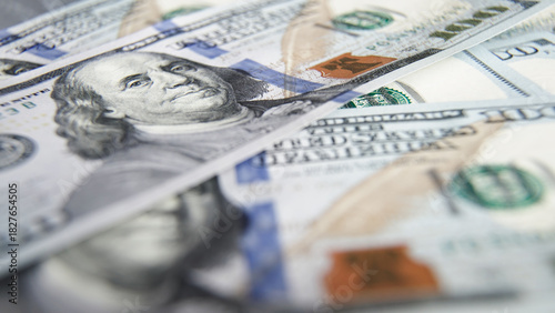 Close-up view of various hundred-dollar bills stacked together, showcasing intricate details and textures of currency, emphasizing wealth and financial transactions