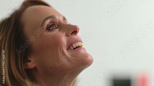 Close-up of a womans face as she smiles and looks up, expressing happiness and contentment.