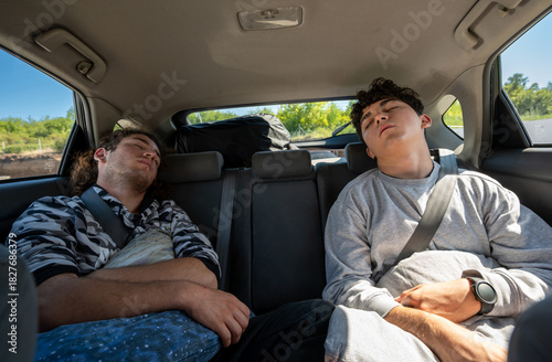 Berlin, Germany, August 10, 2023. Car travel concept: two young people have fallen sound asleep in the back seat. Travel lifestyle, freedom, and relaxation.