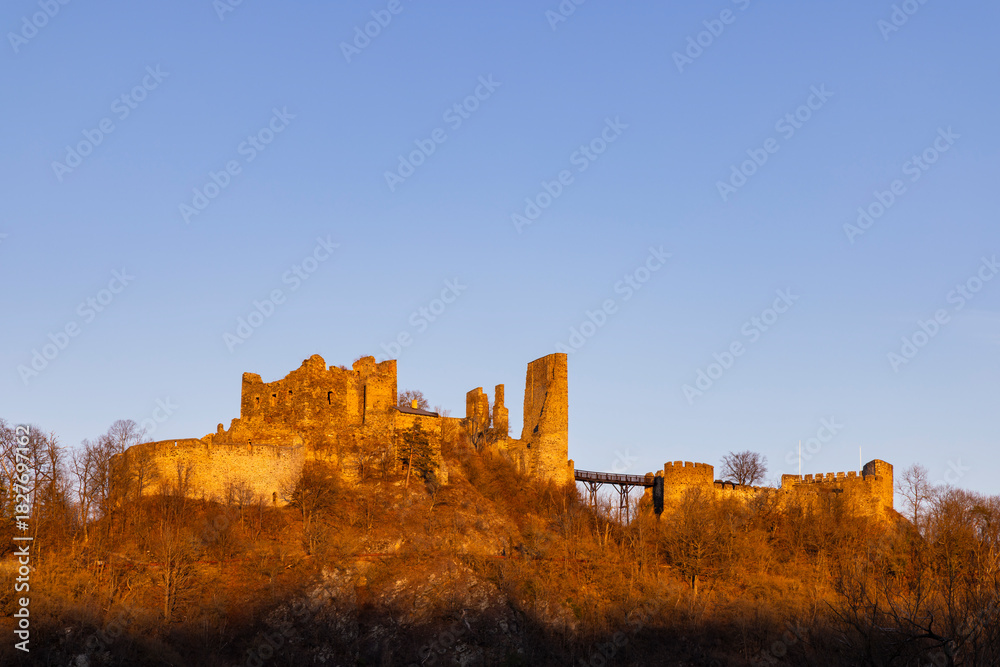 Fototapeta premium Bitov Castle ruins glowing golden at sunset