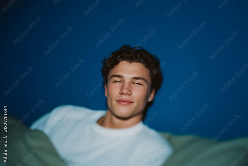 Obraz premium Young Man Lying in Bed Relaxing in Soft Evening Light with Calm Comfortable Mood 