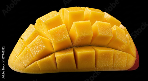 Close up of a ripe mango cut into cubes on a black background showing the juicy yellow flesh of the fruit