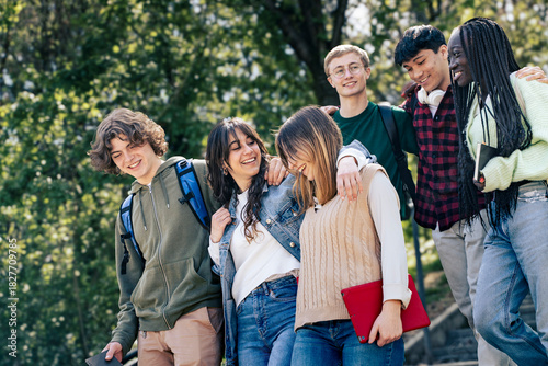 A group of diverse young students walking together outdoors on campus, smiling and enjoying a cheerful moment of friendship and connection.