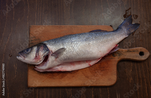 Gutted, ready to cook lavraky fish on a wooden cutting board