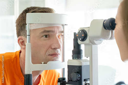 Man undergoing eye examination with a slit lamp in a medical clinic. Diagnostic procedure in ophthalmology, healthcare technology, vision screening.