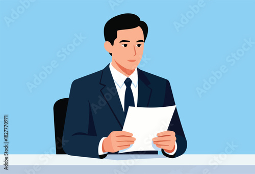 A man in a suit is holding paper in front of him. He is at a desk with a light blue background
