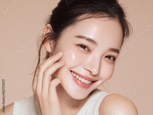 笑顔できらめく綺麗な肌に美容クリームを塗る日本人女性美人モデルの接写写真。スキンケア、コスメ、ビューティーケア広告用