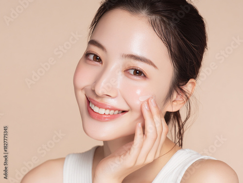 笑顔できらめく綺麗な肌に美容クリームを塗る日本人女性美人モデルの接写写真。スキンケア、コスメ、ビューティーケア広告用