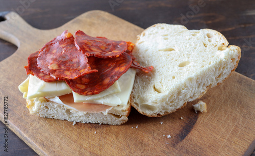 A simple sandwich bread, butter, hamon, cheese, choriso on a cutting board