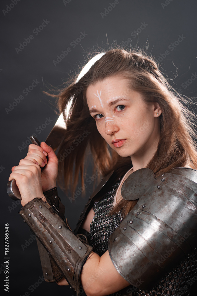 Obraz premium Portrait of a young woman, fantasy warrior in armor with a sword in her hands isolated on a dark background.