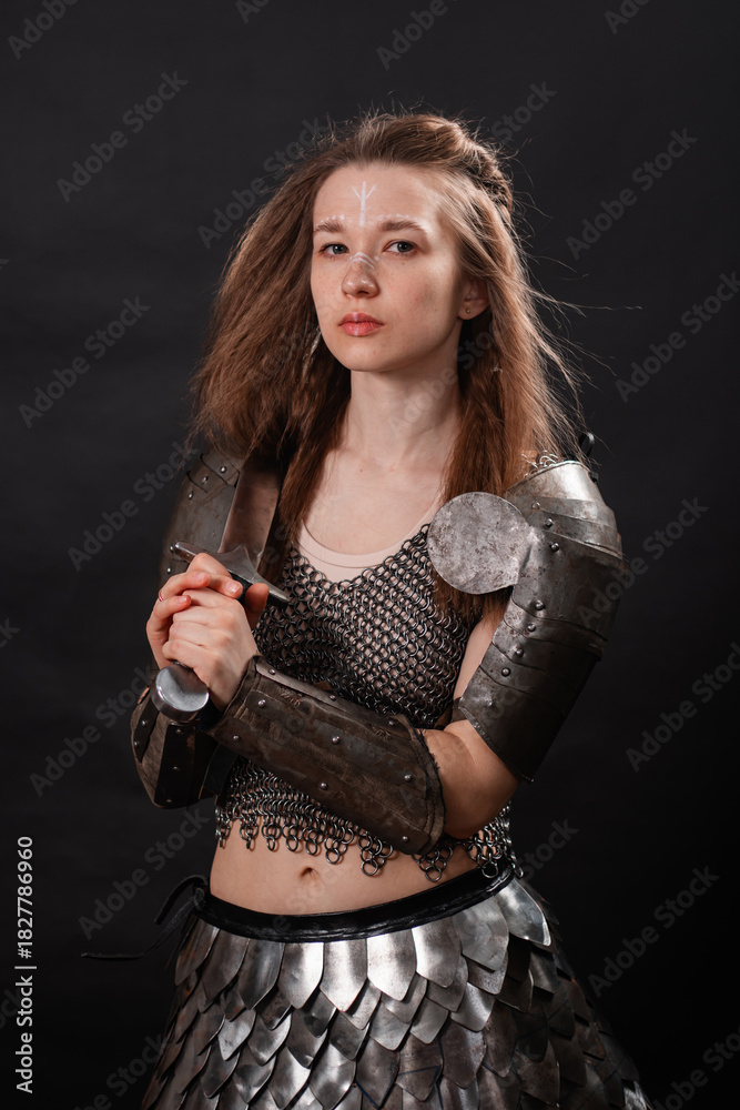 Obraz premium Portrait of a young woman, fantasy warrior in armor with a sword in her hands isolated on a dark background.