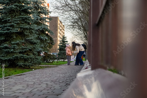 Mother Walking with Child in Urban Neighborhood Holding Drawings