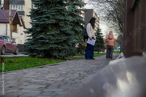 Mother Walking with Child in Urban Neighborhood Holding Drawings