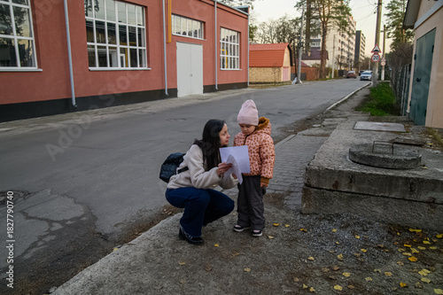 Mother Walking with Child in Urban Neighborhood Holding Drawings
