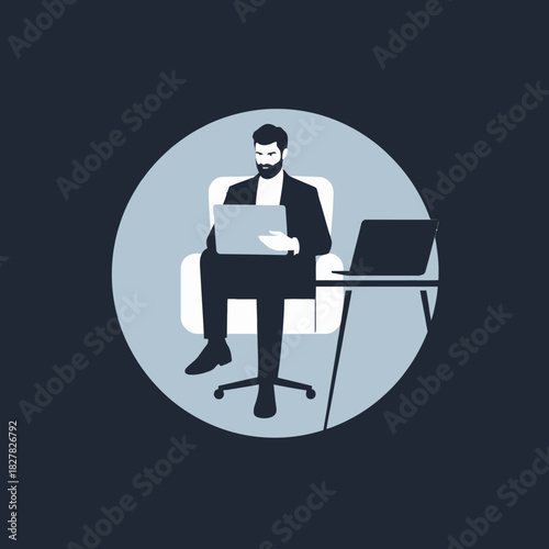 A man in a suit sitting in a chair with a laptop on his lap and another laptop on a desk.