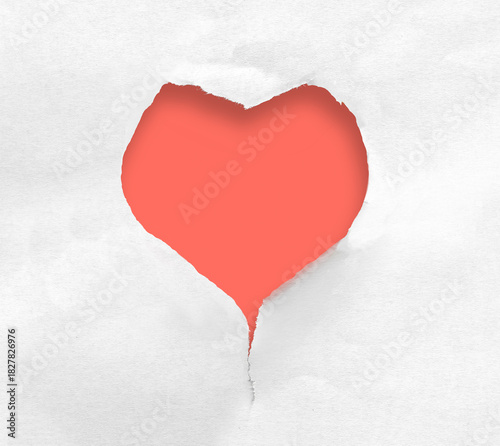 Heart shaped hole in torn paper on red background.
