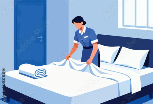 A uniformed person makes a bed with white linen in a minimalist blue-toned room. Rolled towel sits