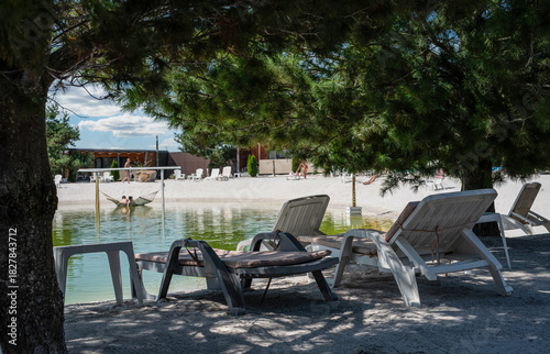 Wallpaper Mural White deck chairs by the lake in the shade between coniferous trees Torontodigital.ca