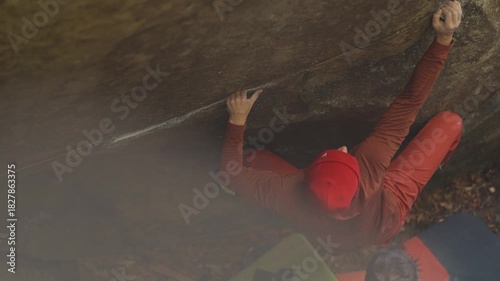 slow motion man climber climbs bouldering on edge of overhanging cliff. man showing high climbing skills, strength and power. healthy lifestyle, active leisure. rock climbing outdoor in autumn forest.