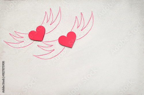Creative sand texture with two wooden red heart and wings drawing on the sand. Valentine's day and love background. Empty place (pattern) for message. Flat lay. Mockup.