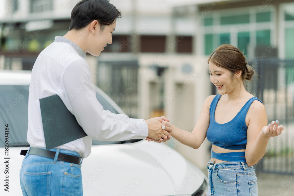 Fototapeta premium Female car dealer shaking hands with man after completing car purchase. Concept of car rental, leasing, insurance and dealership.