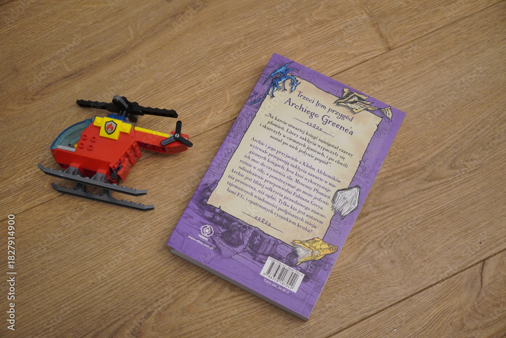 Naklejka premium Lego helicopter toy and book on a wooden surface, top-down view