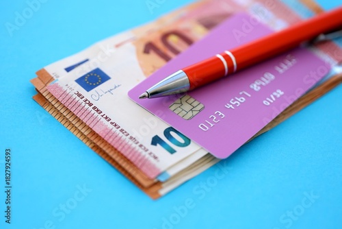 Credit card and pen with euro currency money bills banknotes on light blue background. Business, financial operations and accounting in European Union