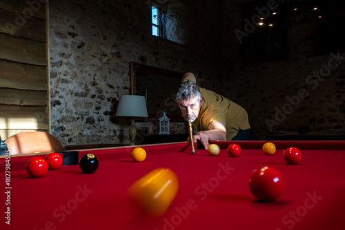 A game of pool with a pool player taking a shot. Motion blur on the yellow ball heading towards camera. 