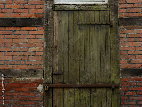 An old wooden door in a brick wall with a padlock.