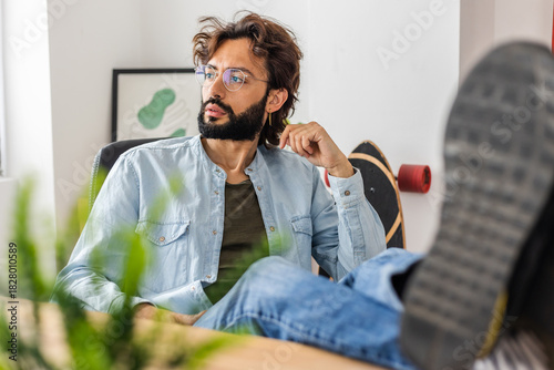 Portrait of young business man looking away while relaxing at home office workplace