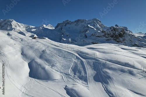 Aerial drone view of snowy alpine terrain near Zermatt, Switzerland, showcasing untouched slopes, ridges, and winter mountain scenery.