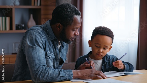 African American family dad assists son with learning teamwork lovely schoolboy with father writing homework at home child kid boy with parent tutor tutoring distant education concentration study