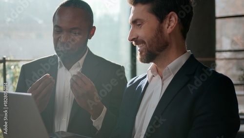 Two smiling men diversity businessmen business team with laptop talking enjoying pleasant communication work with computer Caucasian businessman expert showing idea consulting African American leader