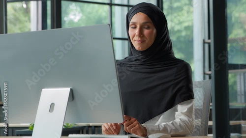 Happy Arabian Muslim business woman typing computer smiling looking at camera Islamic businesswoman female girl in hijab working pc smile posing at table using internet job work project positive glad