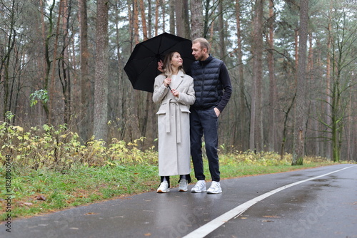 Couple under an umbrella on a wet forest road