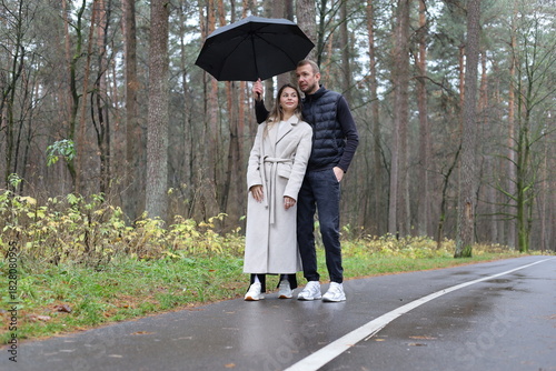 Couple under an umbrella on a wet forest road