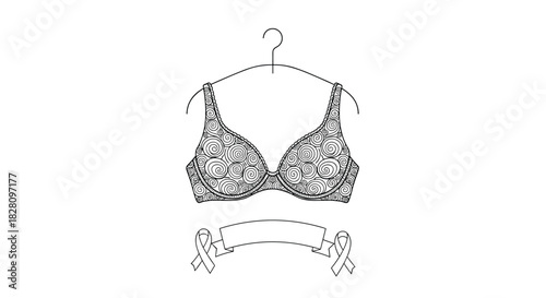 An ornate bra with a swirling pattern on a hanger with a blank ribbon below for Breast Cancer Awareness Month support.