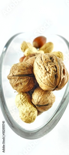 Close-up of walnuts, peanuts and hazelnuts inside a glass dish. Rustic organic snack with natural textures, ideal for healthy lifestyle content, packaging, Christmas food 