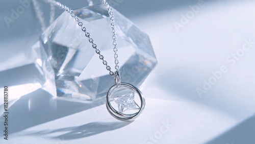 Elegant silver pendant necklace displayed against a reflective crystal background