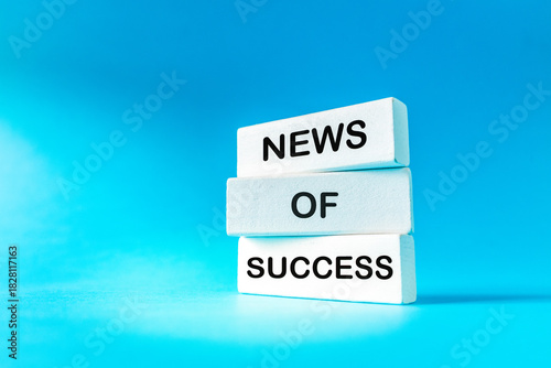 Symbol of a News of success. Conceptual words on wooden blocks. Beautiful blue background. Business and News of Success concept. Copy space.