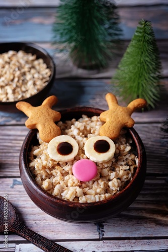 Oatmeal in a bowl in the form of reindeer for Christmas holidays on a wood background