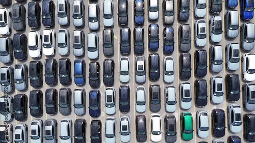 Aerial overhead view of rows of new cars arranged in a large parking lot in the USA.
