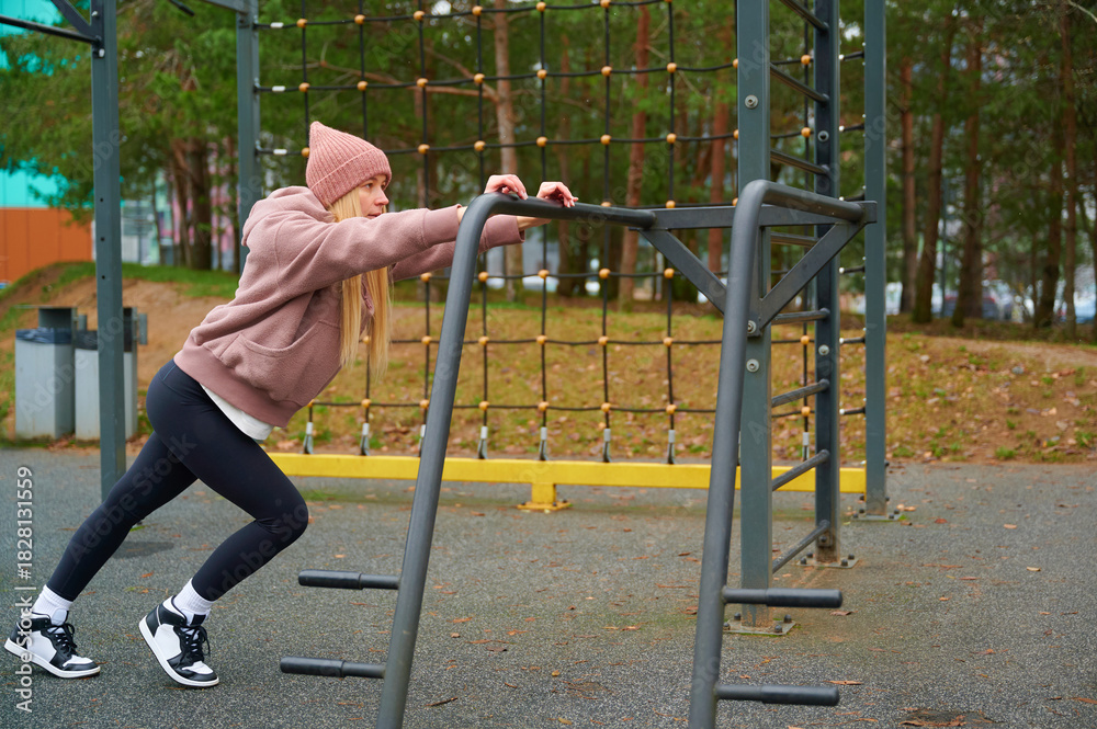 Fototapeta premium Young Woman Stretching at Outdoor Sports Ground in Autumn