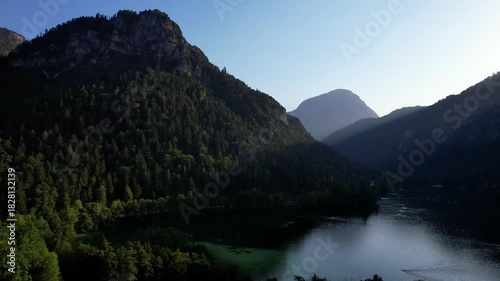 4K Aerial Drone video of Alpine lake Thumsee with turquoise water and lush green woods surrounded by tall mountains at sunset golden hour in Bad Reichenhall Germany