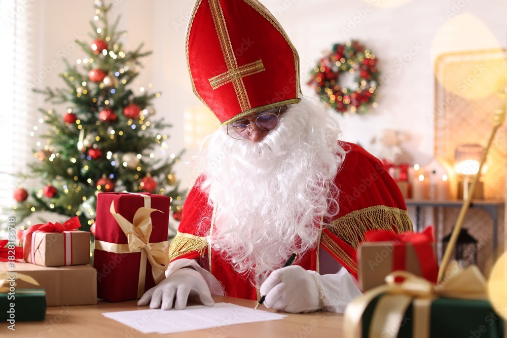 Fototapeta premium Saint Nicholas with letters at desk in room decorated for Christmas