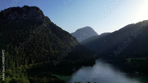 4K Aerial Drone video of Alpine lake Thumsee with turquoise water and lush green woods surrounded by tall mountains at sunset golden hour in Bad Reichenhall Germany