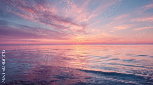 The sky is painted in shades of pink and purple as the sun sets over the tranquil ocean. Gentle waves create a peaceful scene inviting relaxation and reflection along the shoreline.