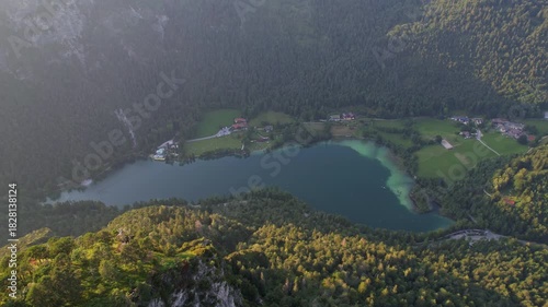 4K Aerial Drone video of Alpine lake Thumsee with turquoise water and lush green woods surrounded by tall mountains at sunset golden hour in Bad Reichenhall Germany