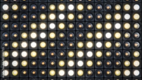 Flashing bright retro studio spot lights or bulbs grid in dark environment making diagonal lines, repeating animation. 