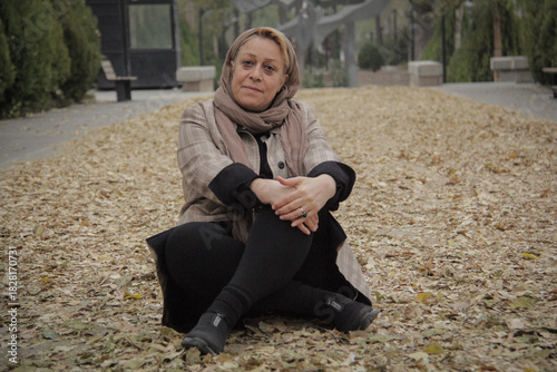 Wallpaper Mural A woman sits among the fallen autumn leaves in the middle of a park walkway Torontodigital.ca